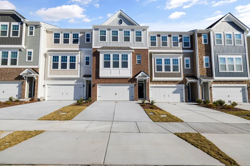 Row of modern townhomes with driveways under a clear sky